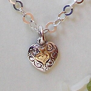 Tiny heart engraved with a wave shape and decorated with tiny gold heart with a delicate silver chain