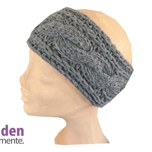 Peut inclure: Un bandeau gris en tricot torsadé présenté sur une tête de mannequin. Le bandeau est fait d'un fil doux et texturé et présente un motif tressé. La marque "faden elemente." est visible en bas à gauche.