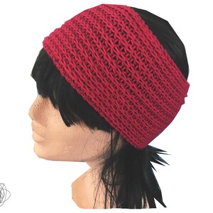 Peut inclure: Un bandeau tricoté rouge vif. La large bande est faite d'un tissu texturé à tissage ouvert. Le bandeau est conçu pour être porté sur le front. L'accessoire est présenté sur une tête de mannequin avec des cheveux noirs.