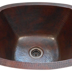 May include: A hammered copper kitchen sink with a square shape and a single drain.