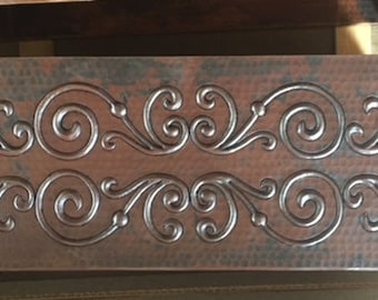 May include: A copper metal drawer front with a hammered finish and an embossed design of swirling vines.