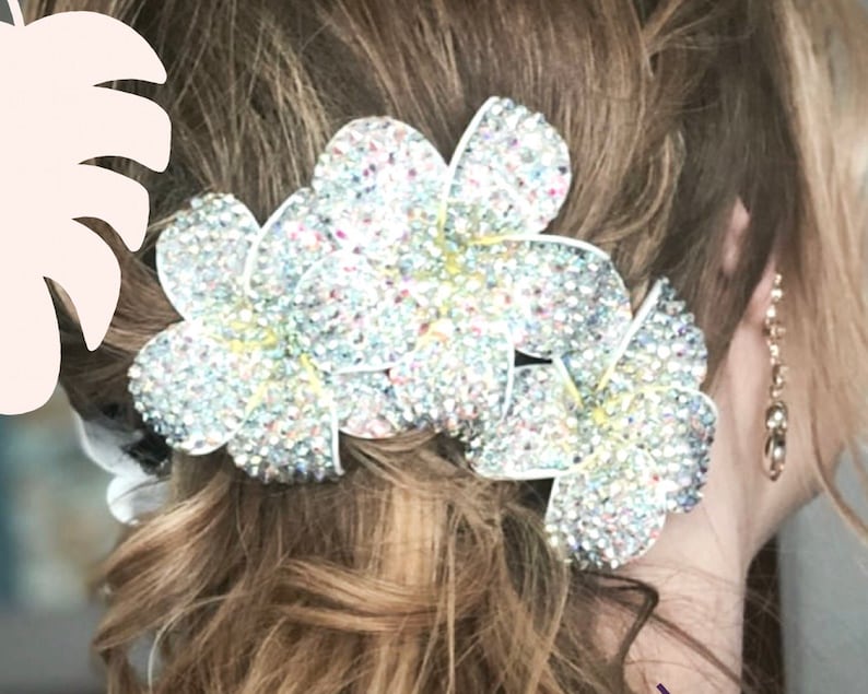 Puede incluir: Un conjunto de tres pinzas para el pelo con forma de flor blanca con pedrer&iacute;a iridiscente. Las pinzas est&aacute;n dispuestas en racimo y son perfectas para a&ntilde;adir un toque de brillo a cualquier peinado.