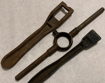 May include: Three rusty metal tools. The tool on the left is a wrench with the word "CHEF" stamped on it. The tool in the middle is a pipe wrench with a round hole in the centre. The tool on the right is a flat chisel with the word "IRWIN" stamped on it.