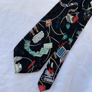 Könnte beinhalten: Schwarze Krawatte mit einem sich wiederholenden Muster aus computerbezogenen Grafiken und Text. Die Krawatte zeigt Illustrationen von Disketten, Laptops und einem abgestürzten System. Der Text enthält "Edit", "Print" und "Laptop".