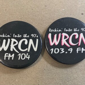 May include: Two black round buttons with white text. The top button says "Rockin' Into the 90's WRCN 103.9 FM". The bottom button says "Rockin' Into the 90's WRCN FM 104".