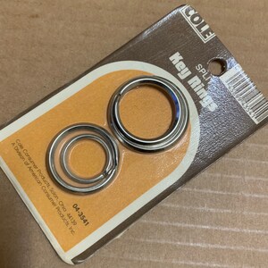 May include: A package of two silver split key rings. The package is brown with yellow text that reads "Cole Key Rings".
