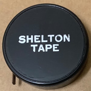 May include: Black tape measure with white text that reads "SHELTON TAPE".