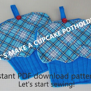 May include: Two blue cupcake-shaped potholders with a plaid pattern in shades of blue and yellow. Each potholder has a blue loop and a red button. The text "LET'S MAKE A CUPCAKE POTHOLDER" is visible.