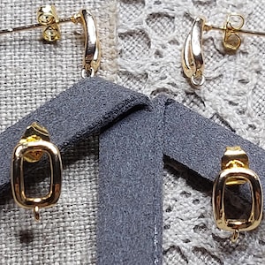 May include: A set of four gold-toned metal earring components. Two pieces feature a curved, arched design with a post back, while the other two pieces are rectangular, open-frame links with a small loop at the bottom for attaching additional jewellery elements.