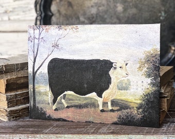 May include: A vintage-style painting of a black and white cow standing in a field. The artwork features a detailed landscape with trees and a building in the background. The painting is on a rectangular canvas.