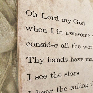 May include: A close-up of a rectangular, aged-looking paper print with black text. The text reads "Oh Lord my God...I see the stars...I hear the rolling..." The paper has a distressed, vintage appearance.