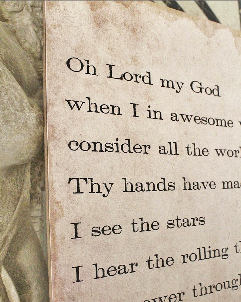 May include: A close-up of a rectangular, aged-looking paper print with black text. The text reads "Oh Lord my God...I see the stars...I hear the rolling..." The paper has a distressed, vintage appearance.