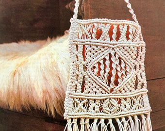 Puede incluir: Un bolso de macramé blanco con flecos en la parte inferior. El bolso está colgado de una silla de madera.