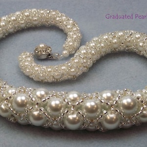 May include: A white pearl necklace with a graduated design. The necklace features large, round pearls interspersed with smaller pearls, all connected by a silver-coloured mesh. The clasp is a silver-coloured, rhinestone-studded closure.