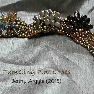 Può includere: Un braccialetto di perline fatto a mano con un design curvo, caratterizzato da gruppi di perline a forma di cono nei toni del marrone, dell'oro e dell'iridescente. Il braccialetto è adornato con perline rotonde più piccole in tonalità simili. Il testo "Tumbling Pine Cones" e "Jenny Argyle (2015)" sono visibili.
