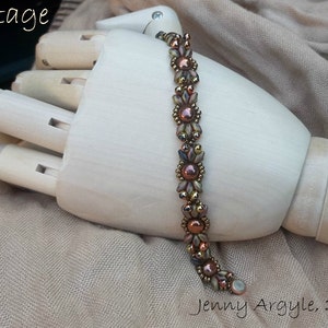 May include: A beaded bracelet with a vintage design. The bracelet features copper-colored beads and accents, with a floral pattern. The text "Vintage Bow" is in the upper left corner, and "Jenny Argyle, 2016" is in the lower right corner.