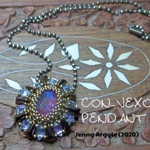 以下が含まれることがあります： オーバル型のイリデセントストーンを中央に配し、金色のビーズと濃い茶色と青紫色のクリスタルで囲まれた手作りのペンダントネックレス。ペンダントはガンメタルボールチェーンから吊り下げられています。画像には「CONVEXOLO PENDANT」と「Jenny Argyle (2020)」と書かれています。
