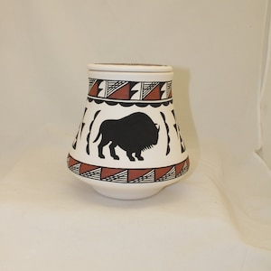 May include: White ceramic jar with a lid, decorated with a black silhouette of a buffalo and geometric patterns in red and black.