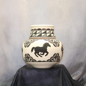 May include: A white ceramic vase with a black silhouette of a horse running. The vase is decorated with geometric patterns in black and brown.