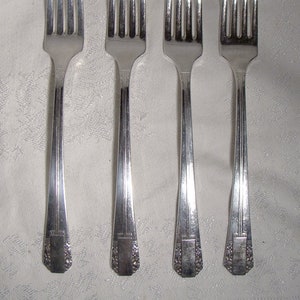 Peut inclure: Quatre fourchettes en argent avec des manches ornés. Les fourchettes ont un design traditionnel avec un manche arrondi et un motif décoratif.