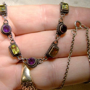May include: A silver necklace with alternating purple and yellow gemstones. The necklace has a delicate chain with a lobster clasp.