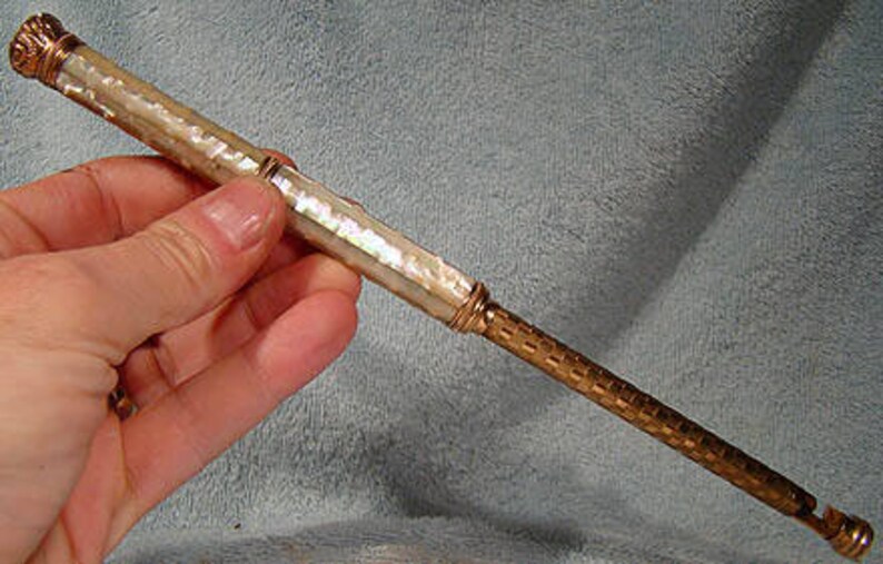 May include: A vintage gold and mother-of-pearl pencil with a decorative top.