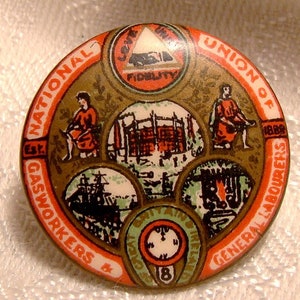 May include: A round, red, white, and gold button with the text "National Union of Gasworkers & General Labourers Est. 1888" around the edge. The center of the button features a triangle with the text "Love, Truth, Fidelity" inside. The button also features four smaller images of workers and their tools.