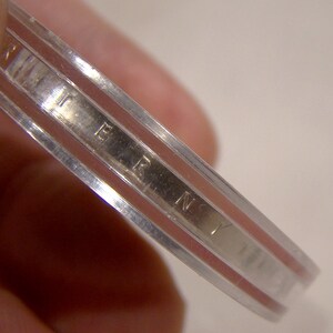 May include: Close-up of the edge of a silver coin with the inscription "LIBERTY" visible.