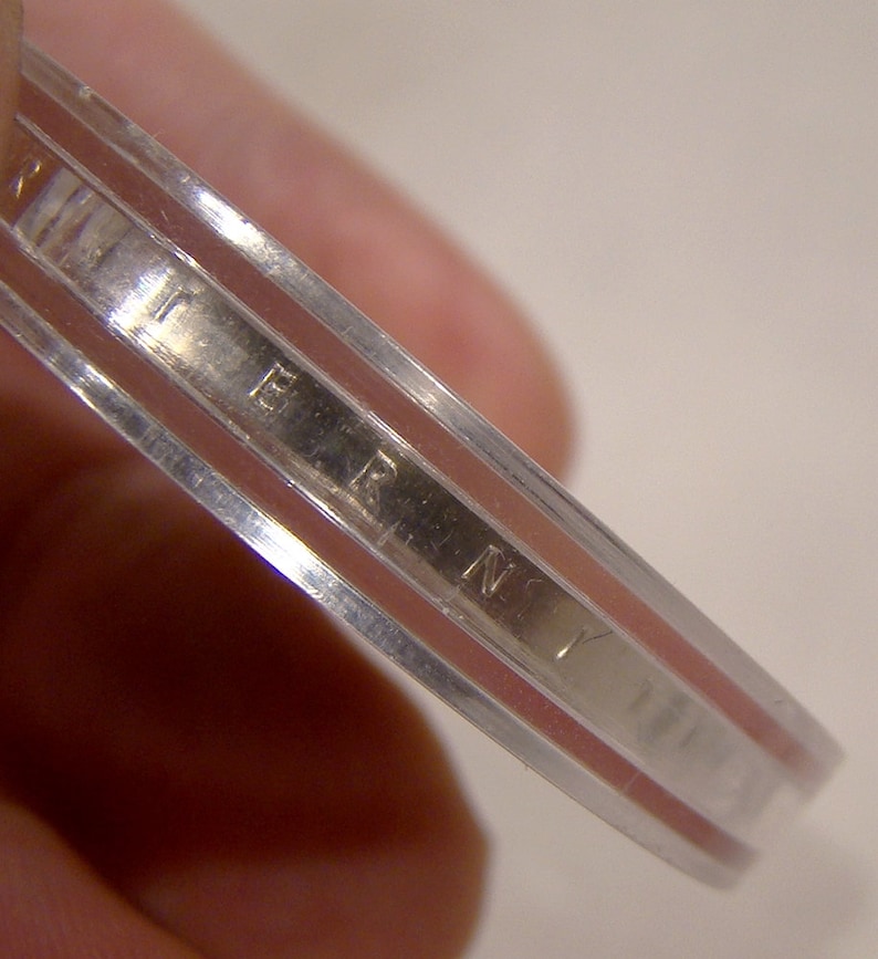 May include: Close-up of the edge of a silver coin with the inscription "LIBERTY" visible.