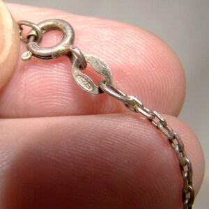 May include: Close-up of a silver chain necklace with a lobster clasp. The clasp has a hallmark that reads "925".