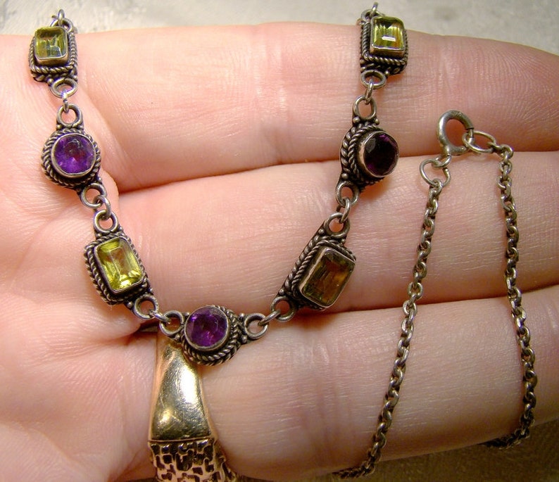 May include: A silver necklace with alternating purple and yellow gemstones. The necklace has a delicate chain with a lobster clasp.