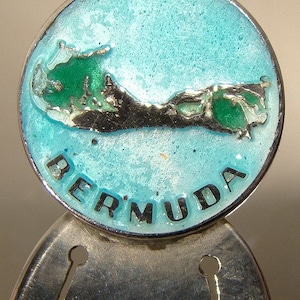 May include: Silver bookmark with a blue and green enamel design of the island of Bermuda. The bookmark has the word "BERMUDA" written in black lettering.