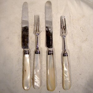 May include: A set of three silver-plated cutlery pieces with mother-of-pearl handles. The set includes a knife and two forks.