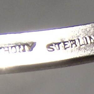 K&ouml;nnte beinhalten: Nahaufnahme eines silbernen Armbands mit dem eingravierten Text "ANTHONY STERLING" auf der Innenseite. Das Armband scheint aus einem gl&auml;nzenden, metallischen Material zu bestehen.