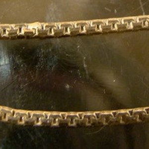 May include: A gold chain necklace with a small, rectangular tag that reads "925 Italy".