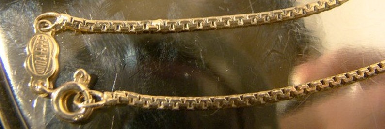 May include: A gold chain necklace with a small, rectangular tag that reads "925 Italy".