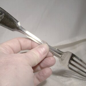 May include: A silver fork with a decorative handle and the inscription "The Old Colony" on the front.