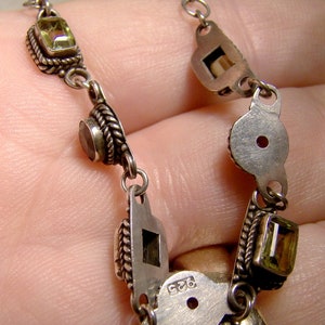 May include: A silver chain necklace with green and brown gemstones. The necklace has a silver clasp with the number 925 stamped on it.