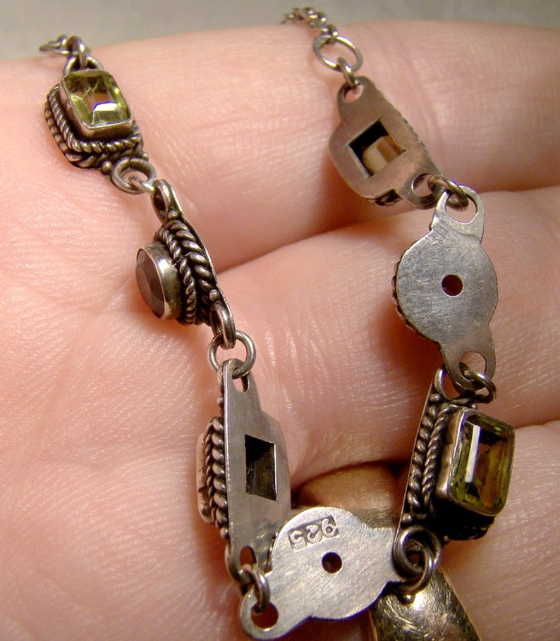 May include: A silver chain necklace with green and brown gemstones. The necklace has a silver clasp with the number 925 stamped on it.