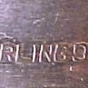 Pu&ograve; includere: Primo piano di un oggetto d'argento con l'iscrizione "STERLING 950" incisa sulla superficie.
