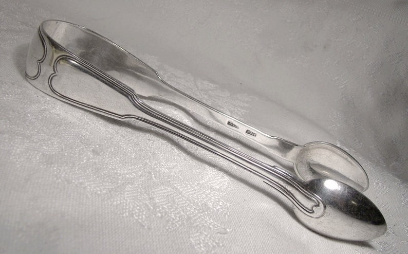 Puede incluir: Pinzas de az&uacute;car de plata con un dise&ntilde;o ornamentado. Las pinzas est&aacute;n hechas de plata pulida y tienen un aspecto cl&aacute;sico y elegante.