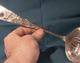 May include: A silver ladle with an ornate handle and a fluted bowl.