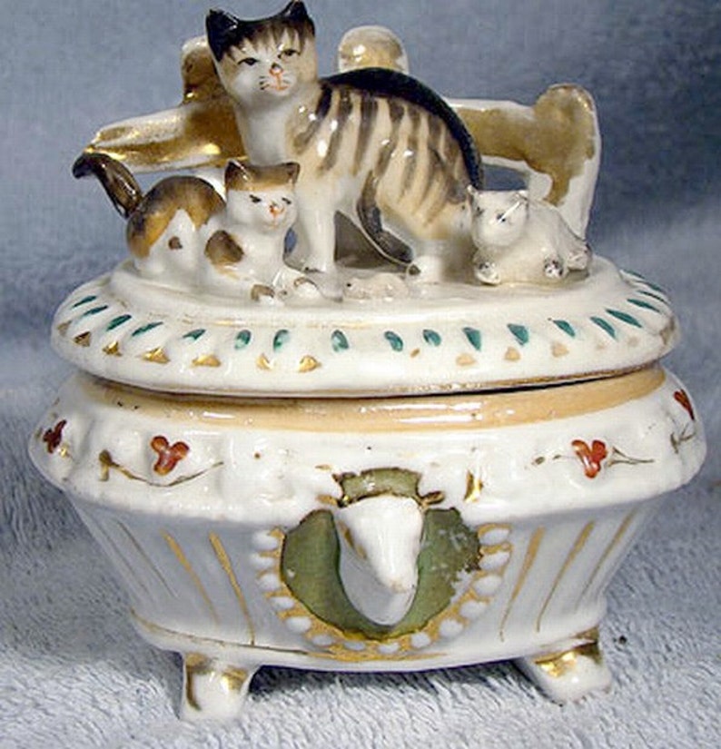 three small china cats on an antique white china casket