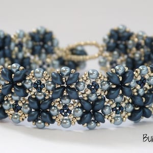 Pode incluir: Um bracelete de contas azul e prata com um design floral. O bracelete é feito com contas pequenas e redondas e tem um visual delicado e feminino.