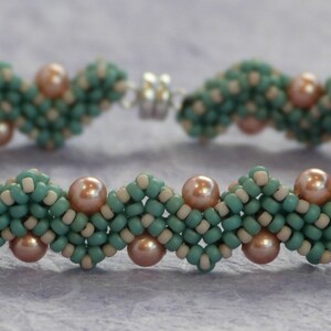 May include: A teal and pink beaded bracelet with a decorative clasp. The bracelet is made with small, round beads in a woven pattern.