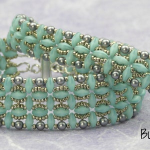 May include: Two beaded bracelets with a light blue and silver color scheme. The bracelets are made with small, oval-shaped beads and round beads.