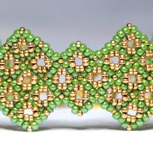May include: A green and gold beaded bracelet with a geometric pattern. The bracelet is made with small seed beads and has a delicate, intricate design.