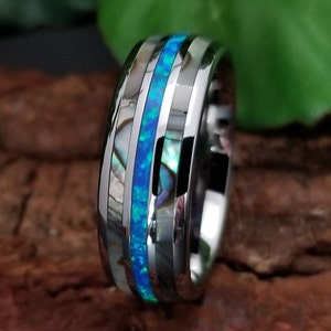 May include: A silver tungsten carbide ring with a blue opal inlay and abalone shell accents.
