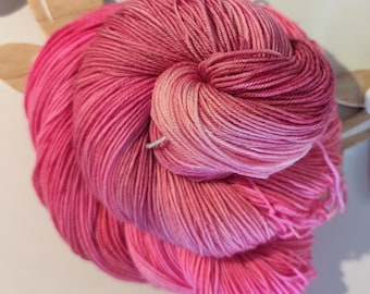 Può includere: Un gomitolo di filato rosa ombré con un gradiente dal rosa chiaro al rosa scuro.