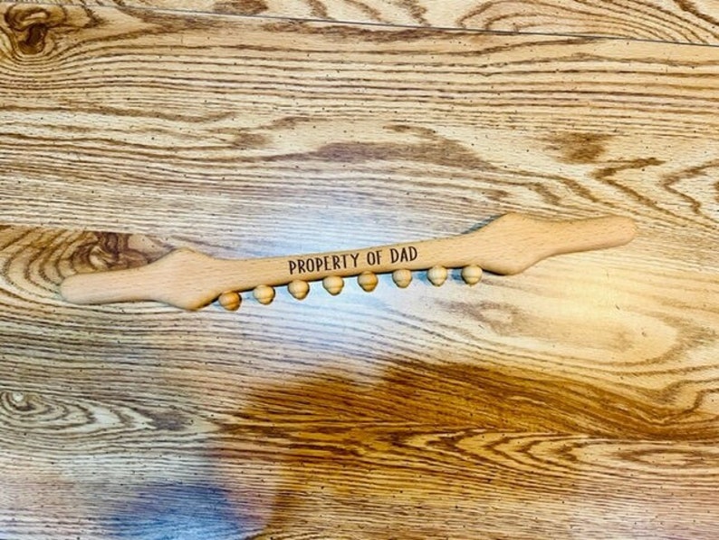 May include: A wooden back scratcher with a row of rounded knobs and the text "PROPERTY OF DAD" engraved on the top.